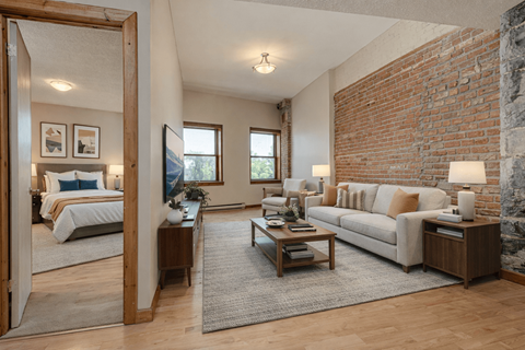 A living room with a white couch and a brick wall.