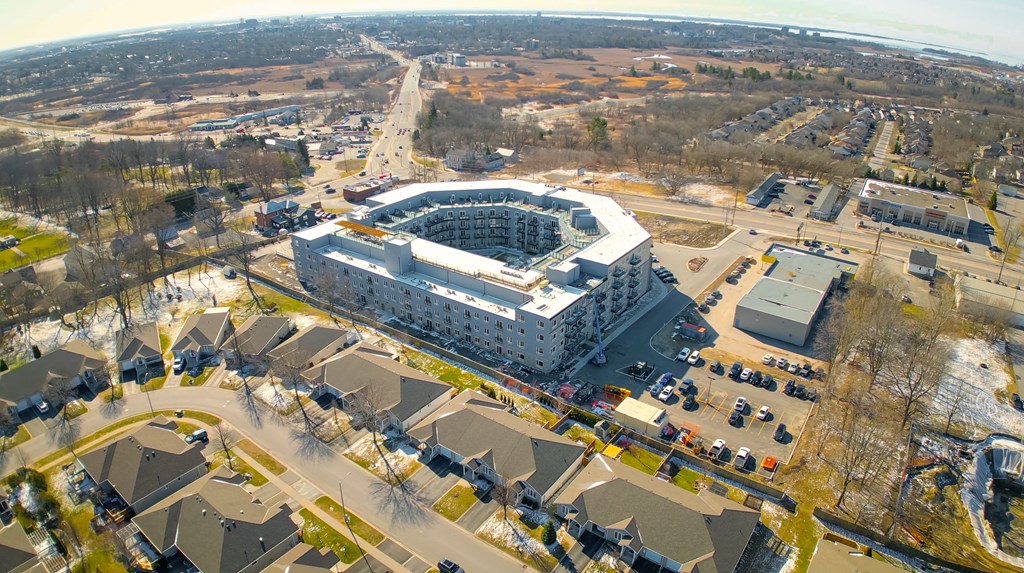 A large white building with a curved roof is surrounded by houses.
