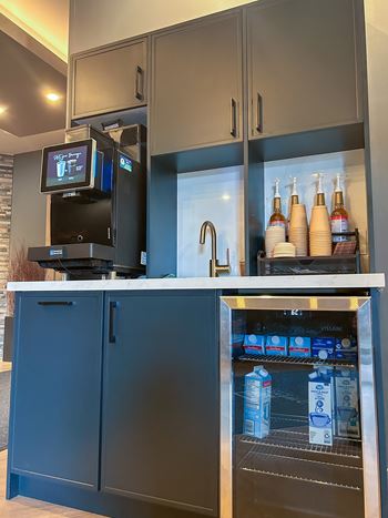 A modern kitchen with a refrigerator and a countertop with a machine on it.