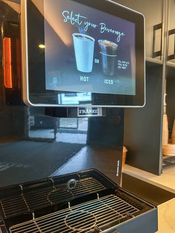 A machine with a screen that says "Select your Beverage" with options for hot or iced.