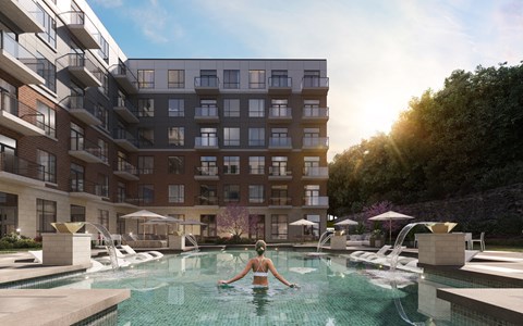 A woman is swimming in a pool surrounded by apartment buildings at The Woods at 180 Kanata Avenue Apartments, Kanata, ON