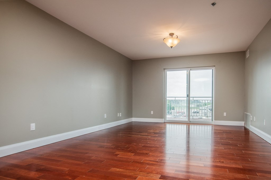 an empty living room with wood floors and a large window