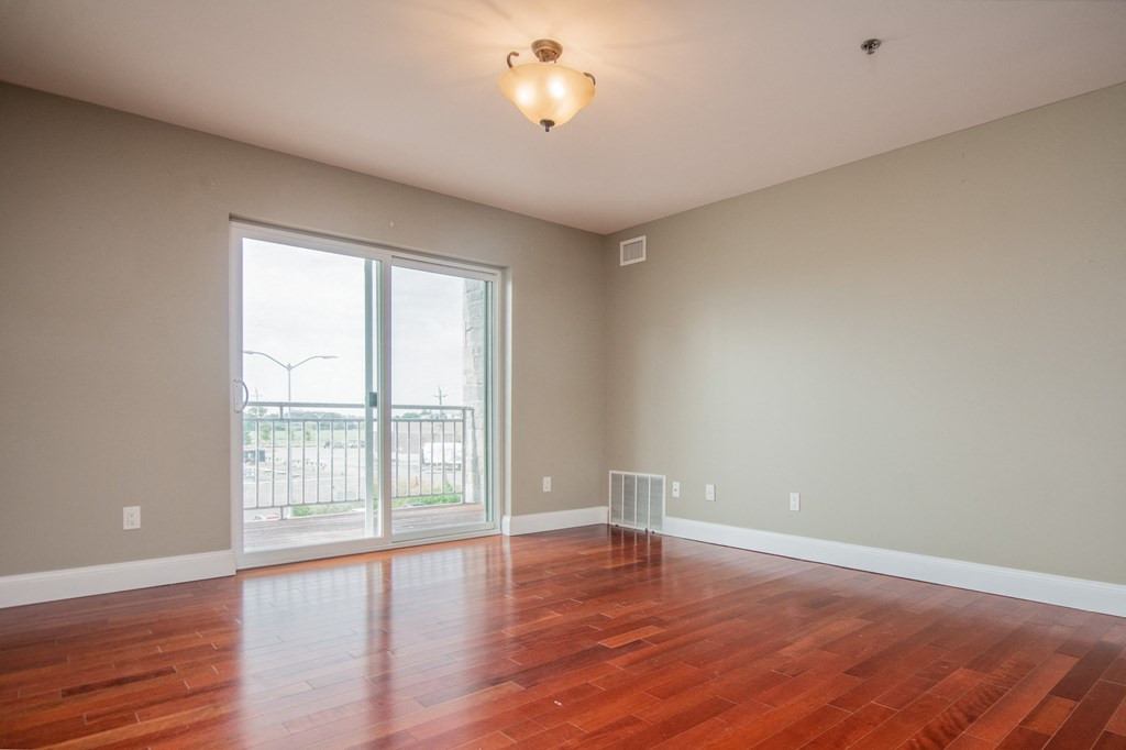 an empty living room with wood floors and a large window