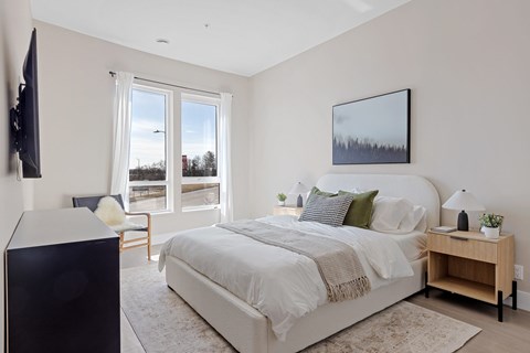 A bedroom with a large bed and a flat screen TV mounted on the wall.