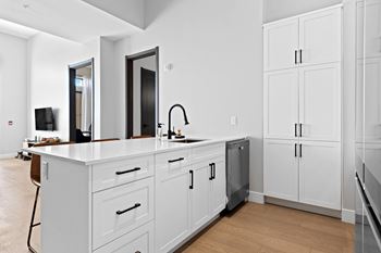 A modern kitchen with white cabinets and a wooden floor at The Woods at 180 Kanata Avenue, ON, K2K 3L9