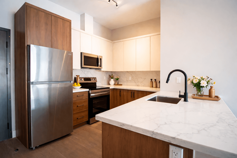 A kitchen with a marble counter top and a refrigerator.