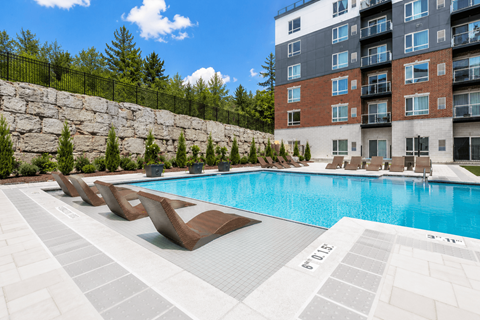 A swimming pool with lounge chairs and a building in the background.