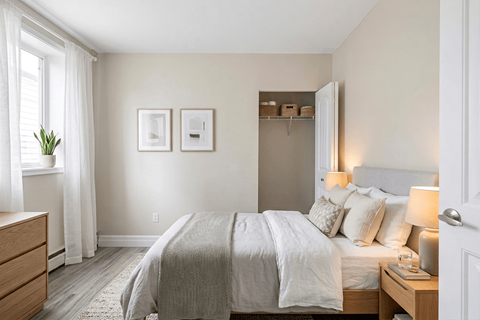 A bedroom with a bed, nightstand, and a window with white curtains.