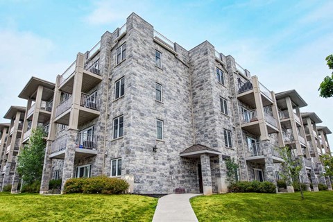 a stone apartment building with balconies and a sidewalk