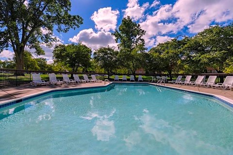 a swimming pool with chairs and trees in the background