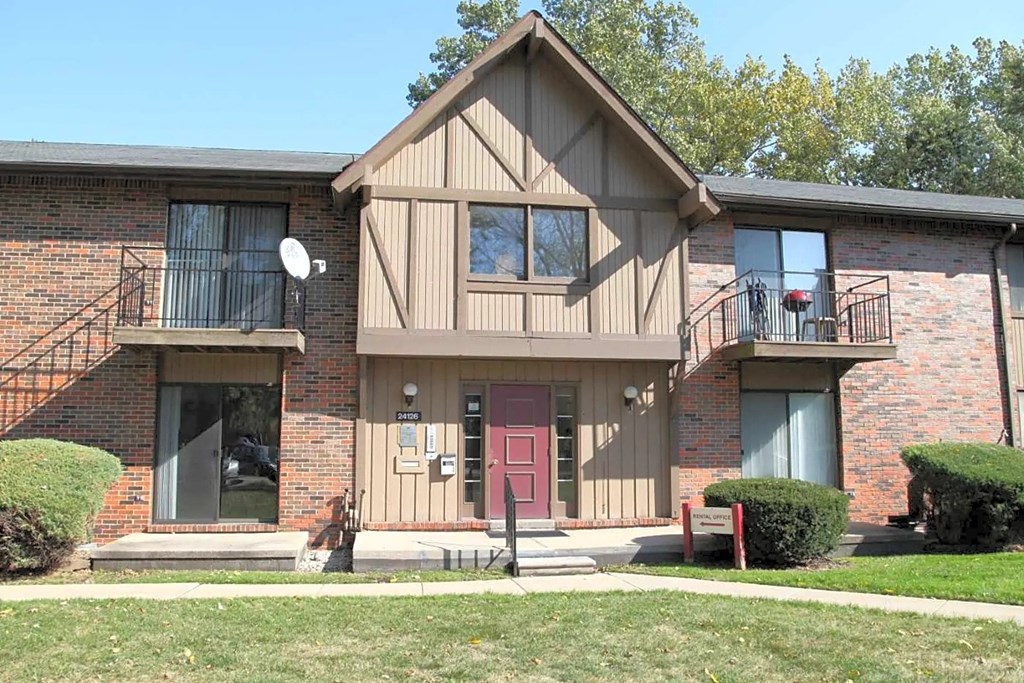 the front of a brick house with a red door