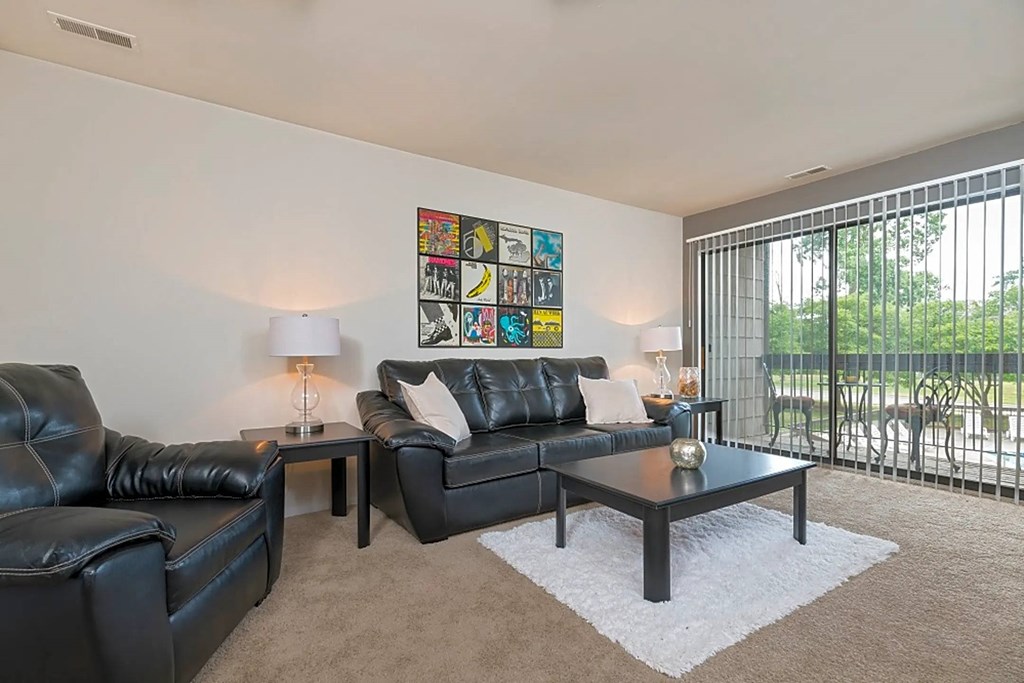 a living room with leather furniture and a sliding glass door