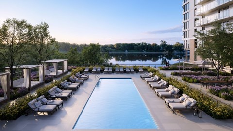 A large swimming pool surrounded by sun loungers and trees.
