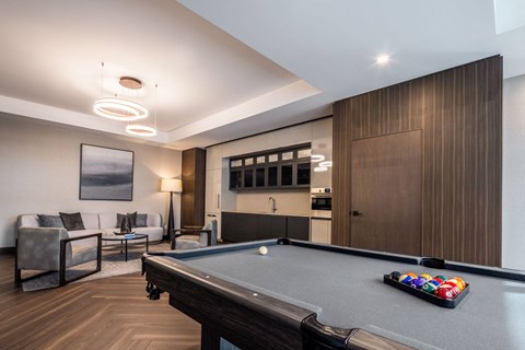 A pool table is in the middle of a room with a couch and a chair.