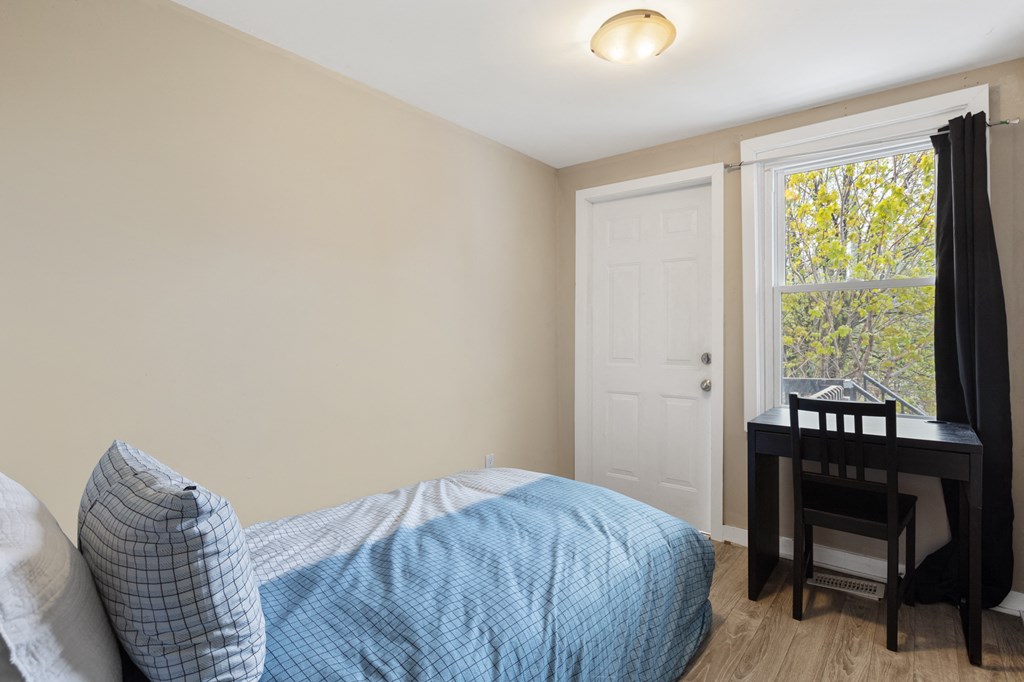 a bedroom with a bed and a desk and a window