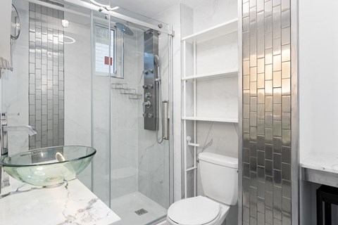 A white toilet sits in a bathroom with a glass bowl on the counter.