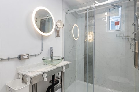 A bathroom with a mirror, a sink, and a shower.