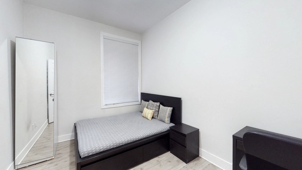 an empty bedroom with a bed and a mirror