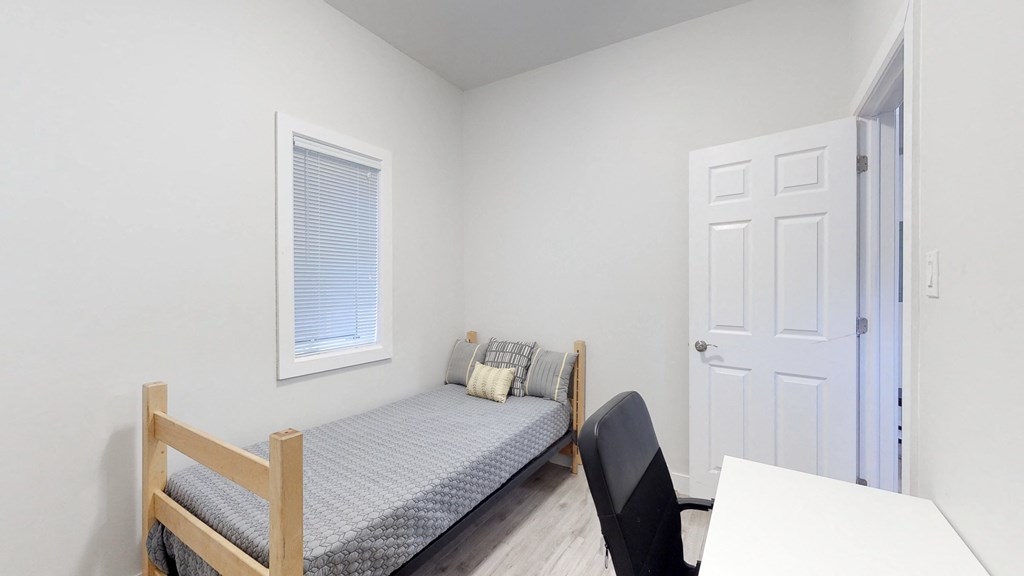 a bedroom with a bed and a desk and a window