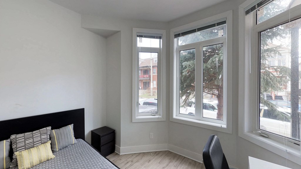 a bedroom with a bed and three large windows