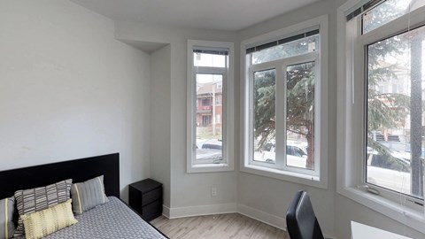 a bedroom with a bed and three large windows