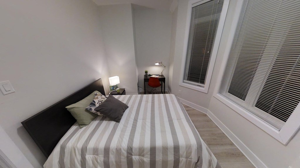 a small bedroom with a bed and two windows