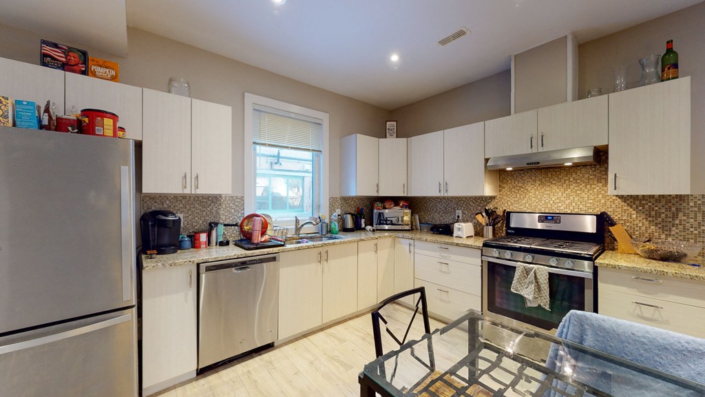 a kitchen with white cabinets and stainless steel appliances and a window