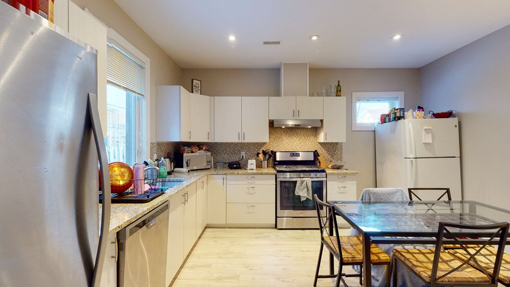 a kitchen with white cabinets and a table and chairs