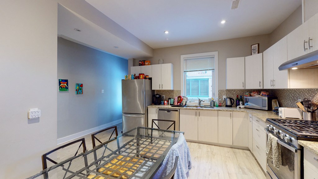 a kitchen with white cabinets and stainless steel appliances and a glass table