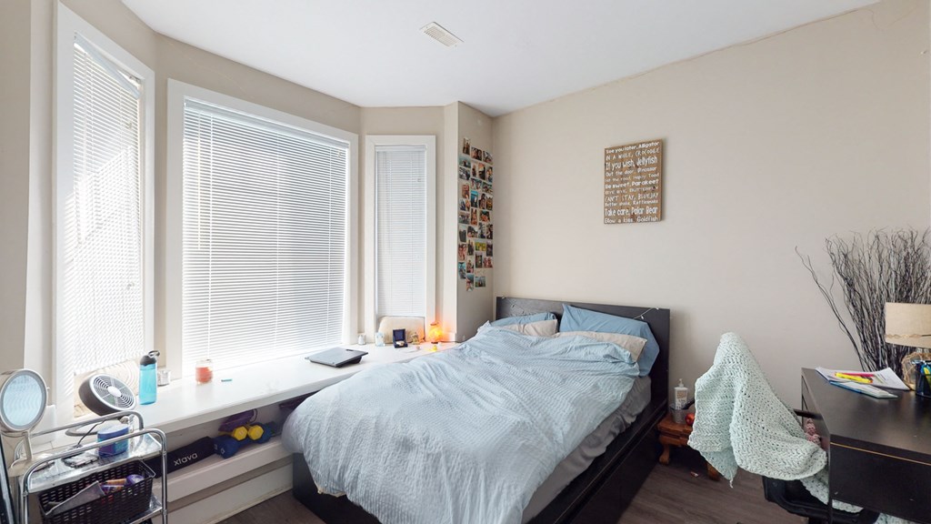 a bedroom with a bed and a desk and three windows