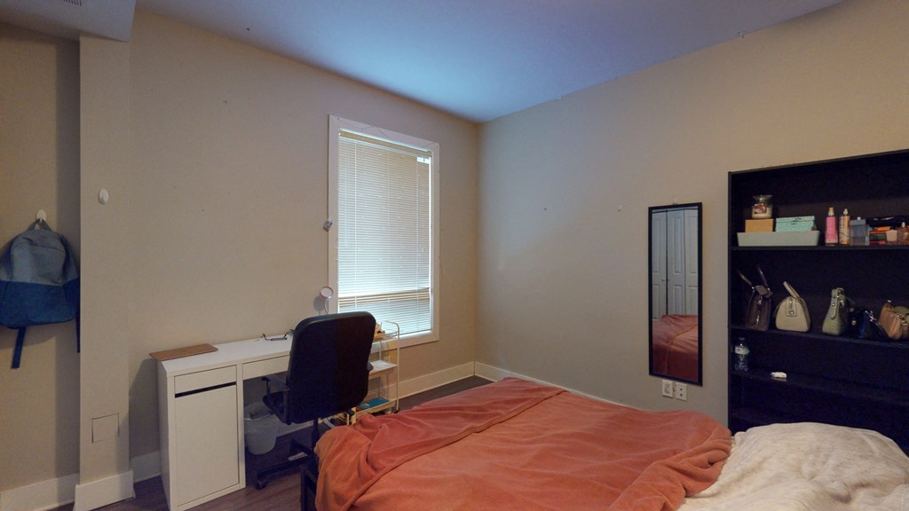 a bedroom with a bed and a desk and a window