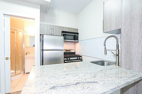 a kitchen with a marble counter top and a stainless steel refrigerator