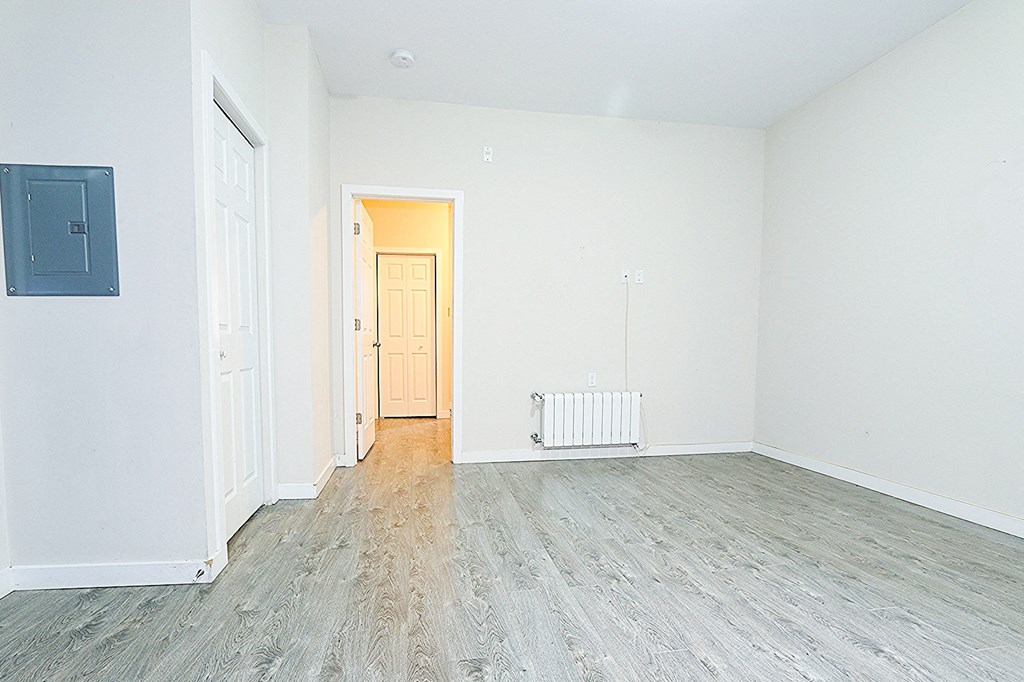 an empty living room with wood floors and white walls