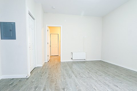 an empty living room with wood floors and white walls
