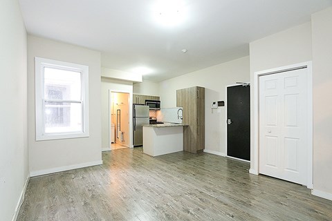 a renovated living room with a kitchen and a wood floor