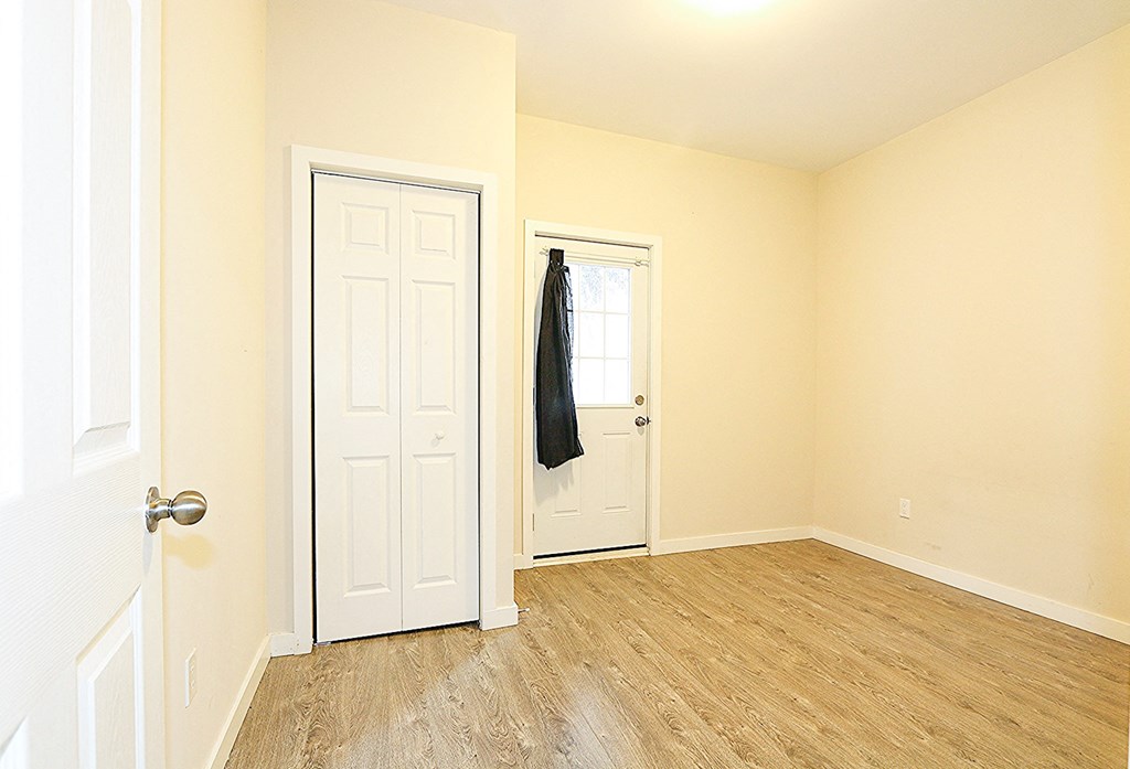 an empty bedroom with a white door and wood floors