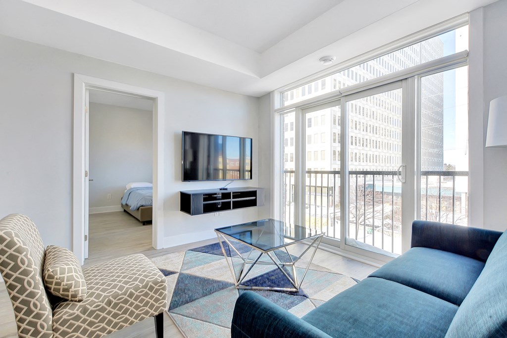 a living room with a blue couch and a glass coffee table and a large window