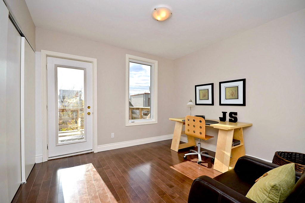 a living room with a desk and a door to a balcony