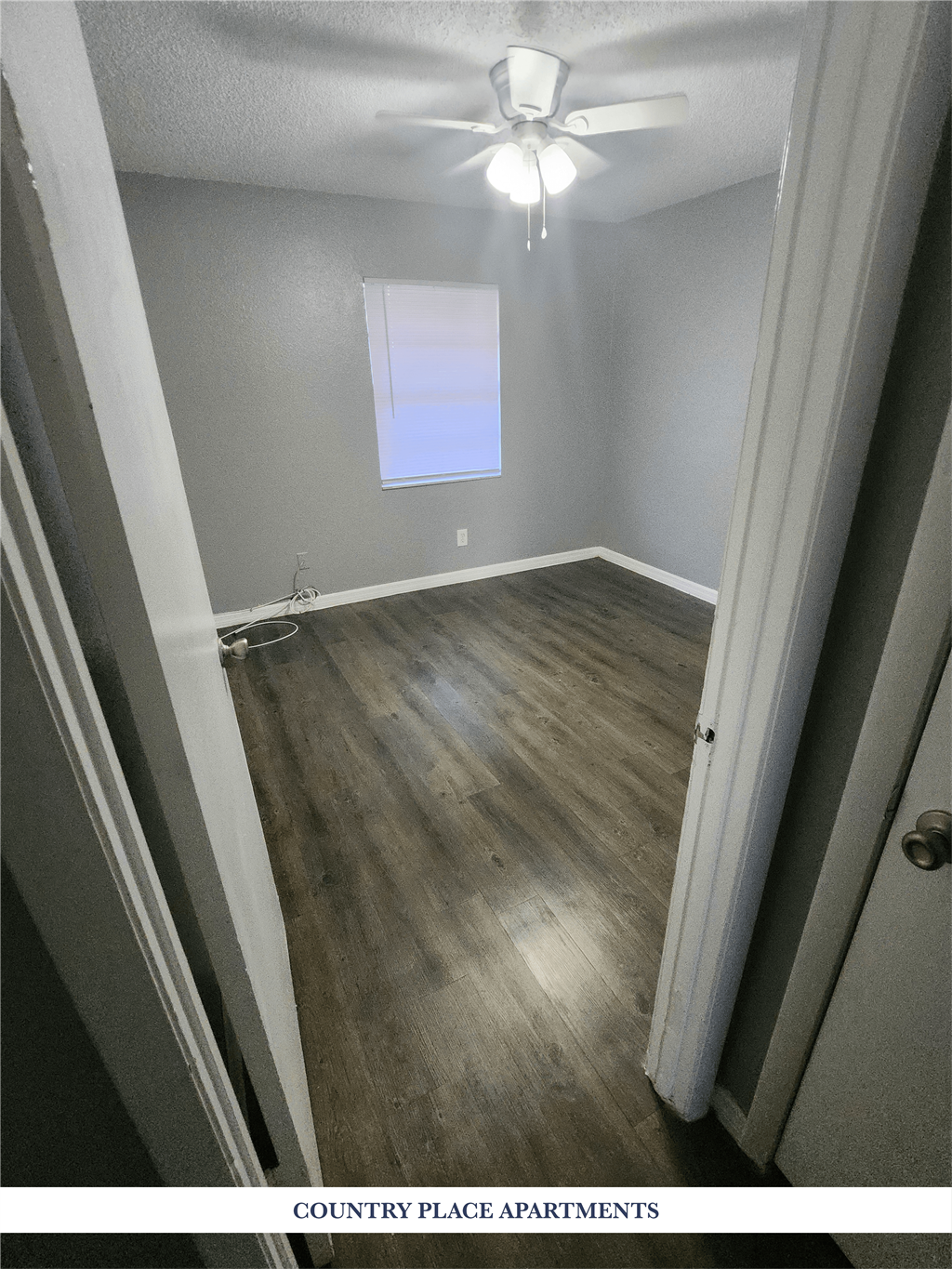 A room with wooden floors and a ceiling fan.