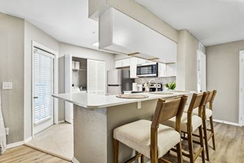 a kitchen with a bar with four chairs at Reserve at Temple Terrace, Temple Terrace