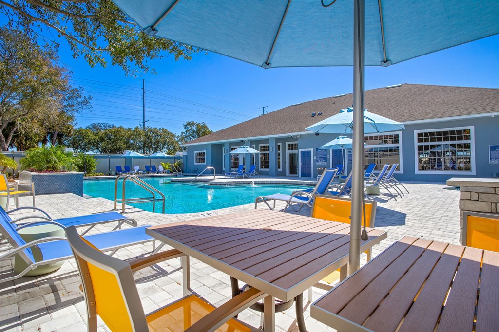 tables and chairs around a pool with the clubhouse in the background at Reserve at Temple Terrace, Temple Terrace, FL