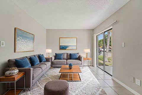 A living room with a grey couch, a coffee table, and a painting on the wall.