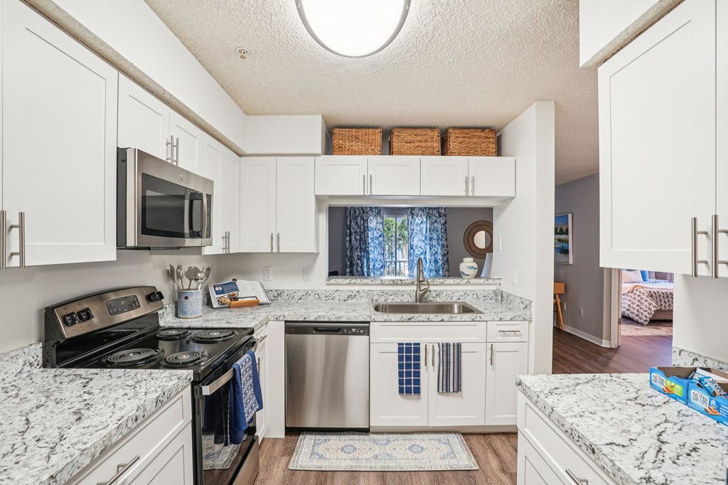A kitchen with white cabinets and marble countertops.