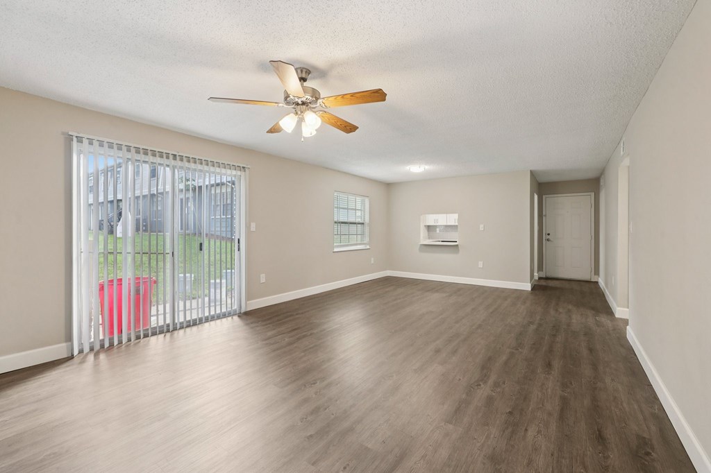 A room with a ceiling fan and sliding glass doors.