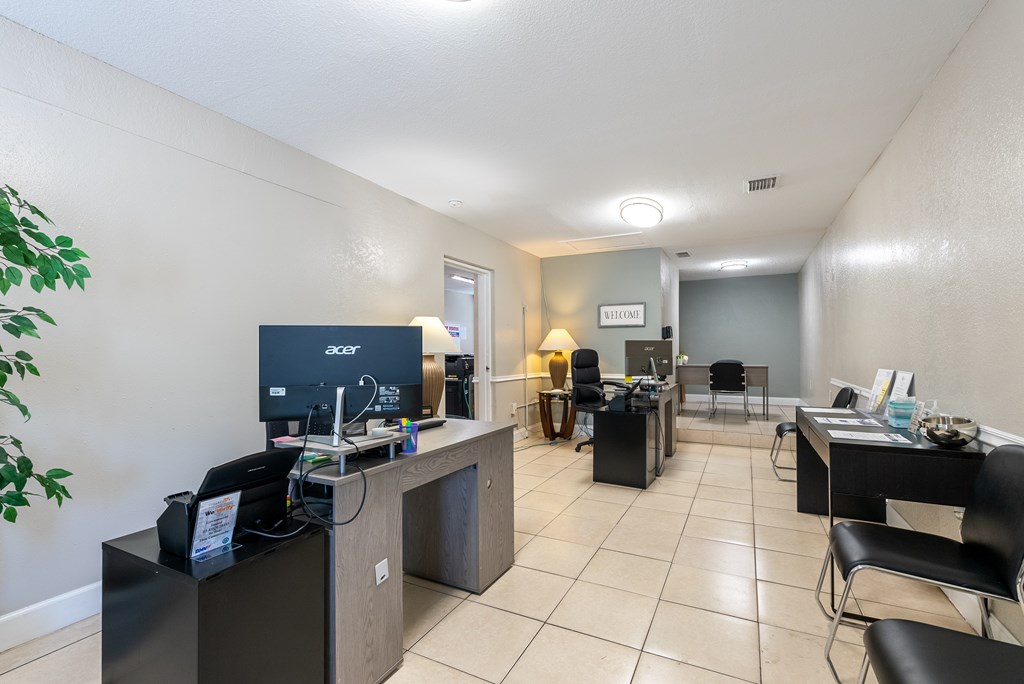 A room with a desk, chairs, and a computer monitor.