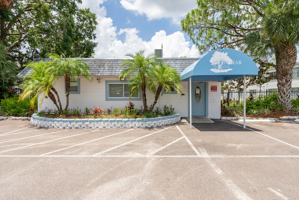 A small building with a blue awning is surrounded by a parking lot.