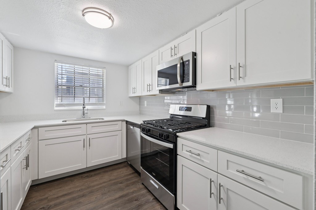 A kitchen with white cabinets and a black stove top oven.