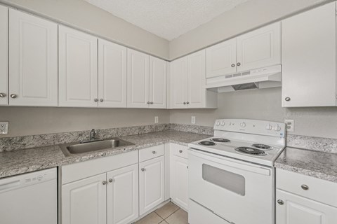 A kitchen with white cabinets and a white stove top oven.