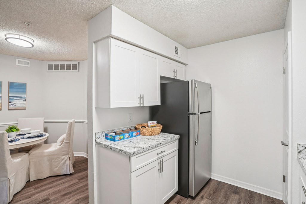 A kitchen with a black refrigerator and white cabinets.