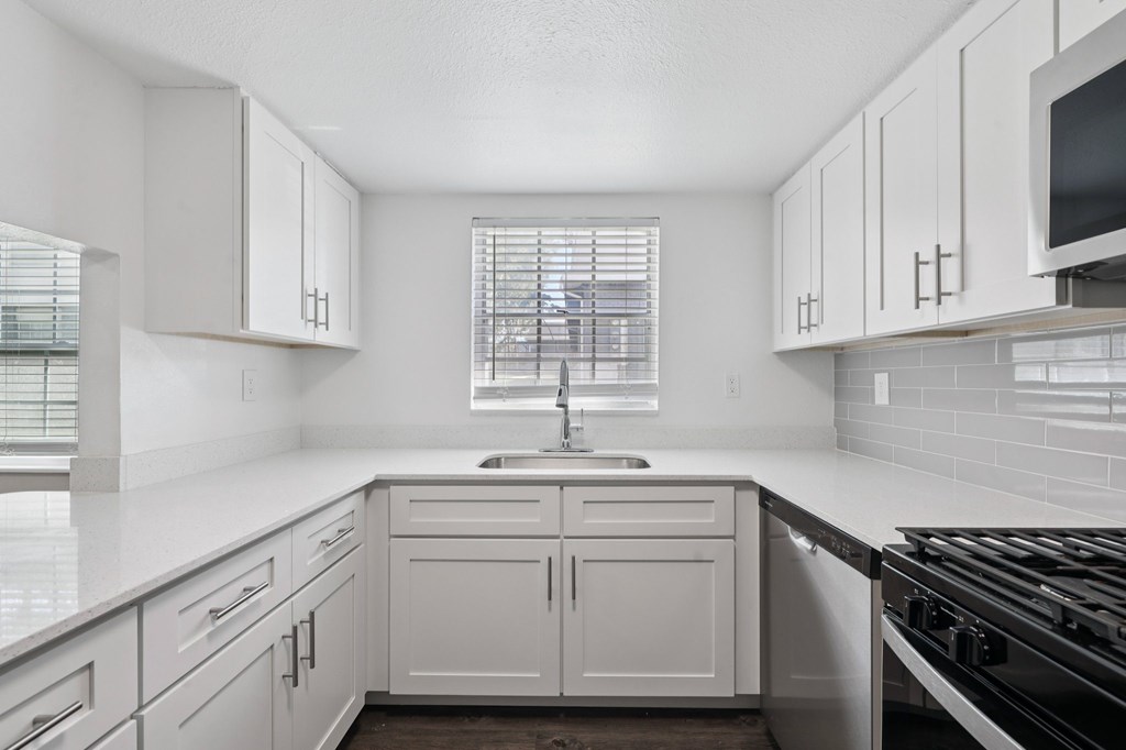 A kitchen with white cabinets and a black stove top.